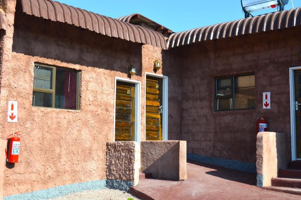 A building with two doors, a fire extinguisher, and a fire hose on the ground.