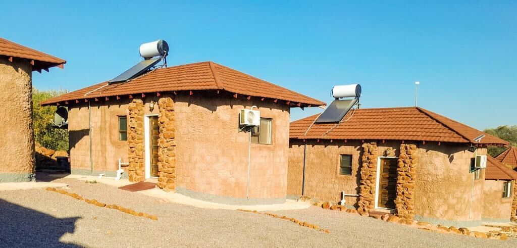 A row of rustic stone buildings with sloped roofs, each equipped with a satellite dish.