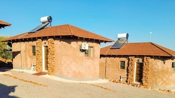 A row of rustic stone buildings with sloped roofs, each equipped with a satellite dish.