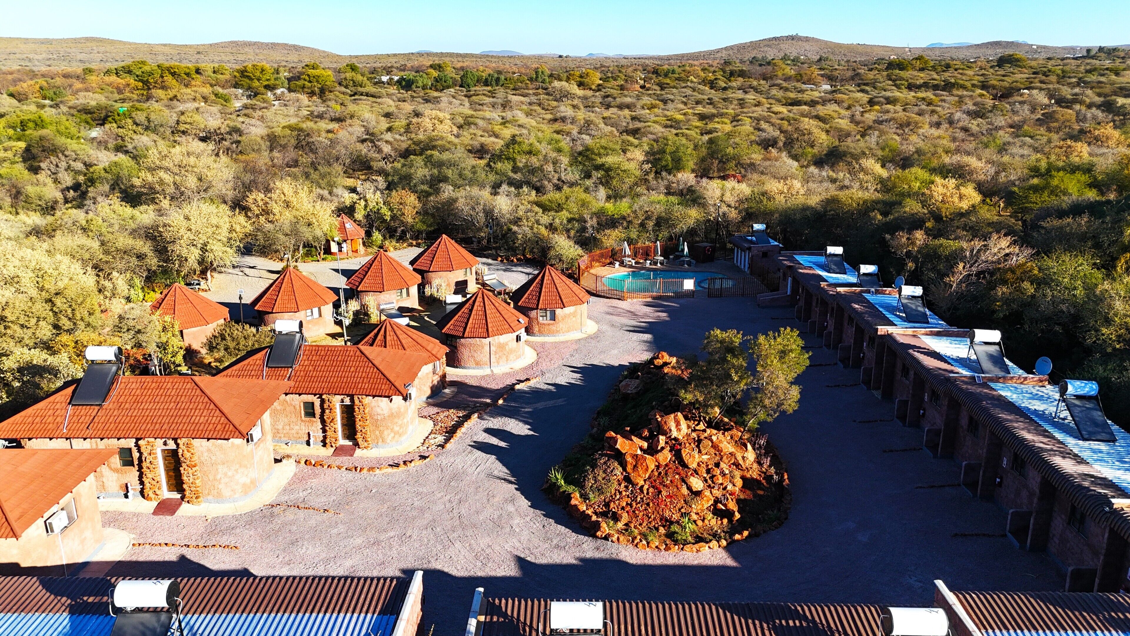 A resort with multiple round-roofed buildings, a swimming pool, and a rocky garden area.