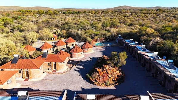 A resort with multiple round-roofed buildings, a swimming pool, and a rocky garden area.