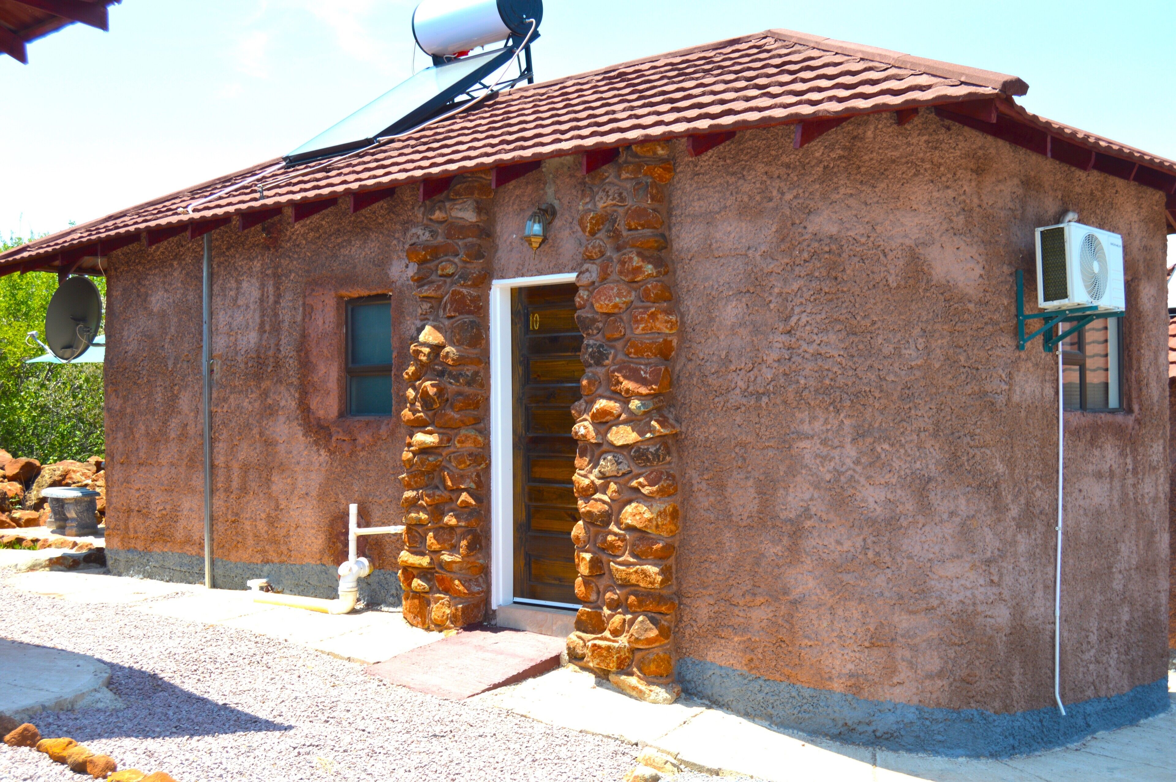 A small stone building with a tiled roof, a door, and a satellite dish.