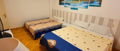 Une chambre d’hôtel avec deux lits, une grande fenêtre et un mur orné de trois tableaux.