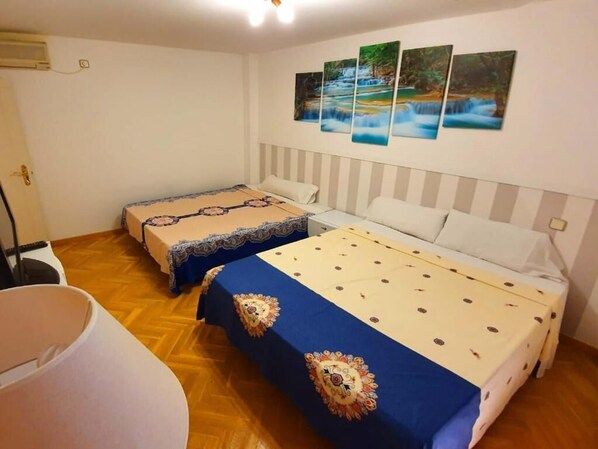 A hotel room with two beds, a large window, and a wall with three paintings.