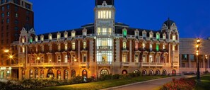 A large, historic building with multiple balconies and a central tower, likely a hotel or public building.