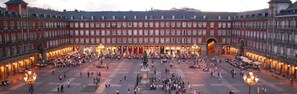 A historic courtyard with a central statue, surrounded by buildings with multiple floors and balconies.