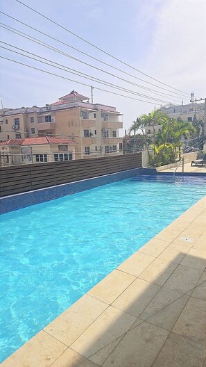 Ein Swimmingpool mit klarem, blauem Wasser, umgeben von einer gefliesten Liegefläche.