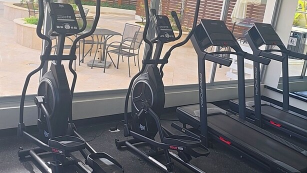 Ein Fitnessraum mit Ergometer, Laufbändern und einer Hantelbank.
