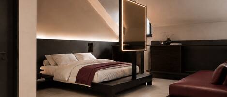Un dormitorio moderno con cama, mesitas de noche, lámpara de noche, sofá y espejo montado en la pared.
