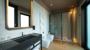 Un baño moderno con un espejo grande, lavamanos dobles, cabina de ducha de vidrio y suelo de madera.