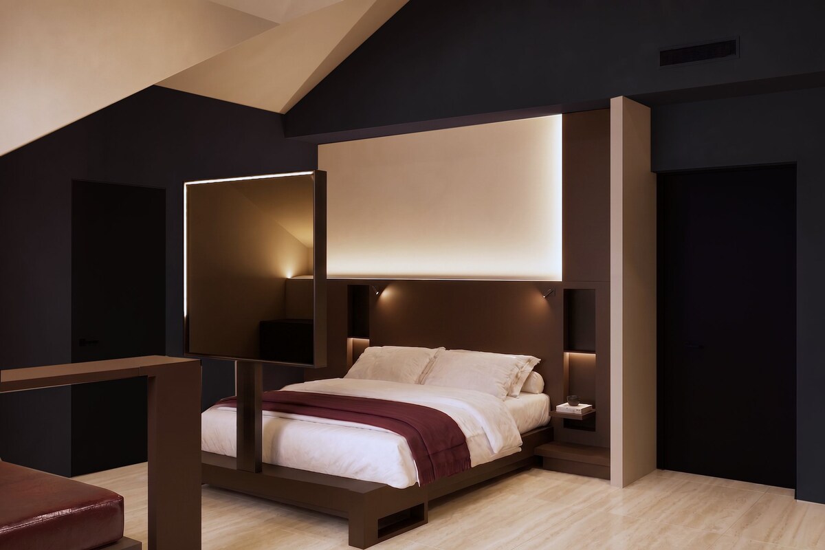 A modern bedroom with a bed, bedside tables, and a desk.