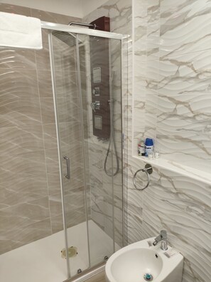 Un bagno moderno con doccia vetrata, lavandino bianco e pareti con decorazione marmorizzata.