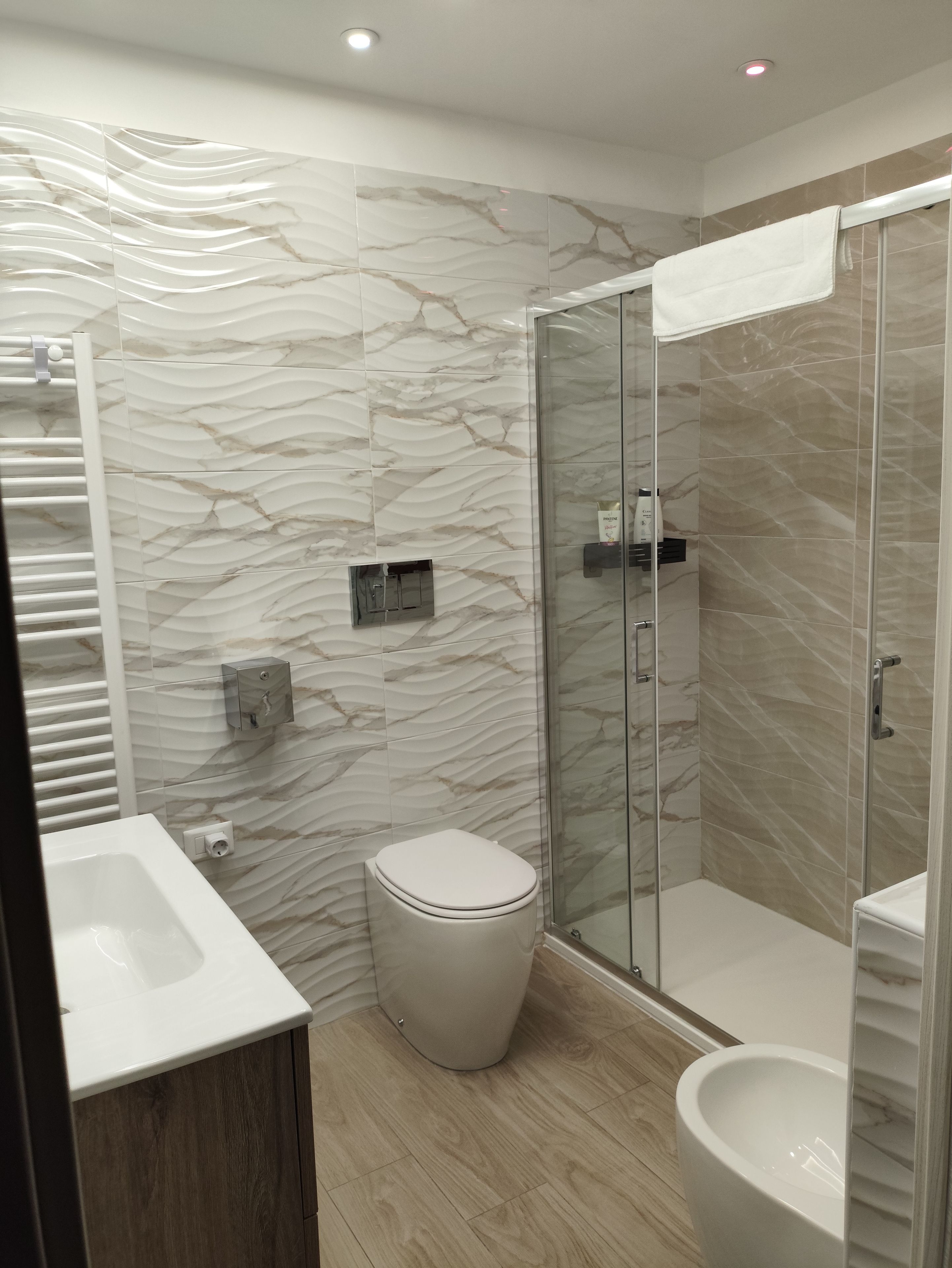 Un bagno moderno con cabina doccia in vetro, un water e un lavandino.