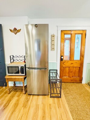 A kitchen with a stainless steel refrigerator, a microwave, and a wooden table. - Ancestral Charming Home - Central Downtown Charlottetown (Charlottetown)
