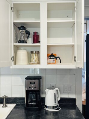 A kitchen with a coffee maker, a kettle, and a cabinet with various containers. - Ancestral Charming Home - Central Downtown Charlottetown (Charlottetown)