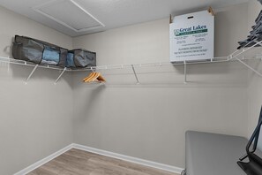 A room with a white ceiling, a grey wall, and a grey floor. There is a white shelf with a sign for Great Lakes Carpet & Tile, and a grey chair.