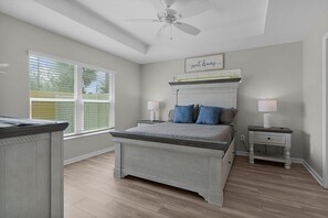 A bedroom with a bed, bedside tables, a ceiling fan, and a window with blinds.
