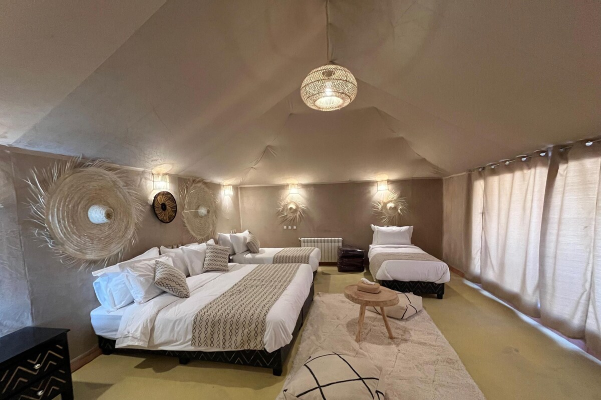 Una camera da letto con due letti, un tavolo rotondo e applique decorative.