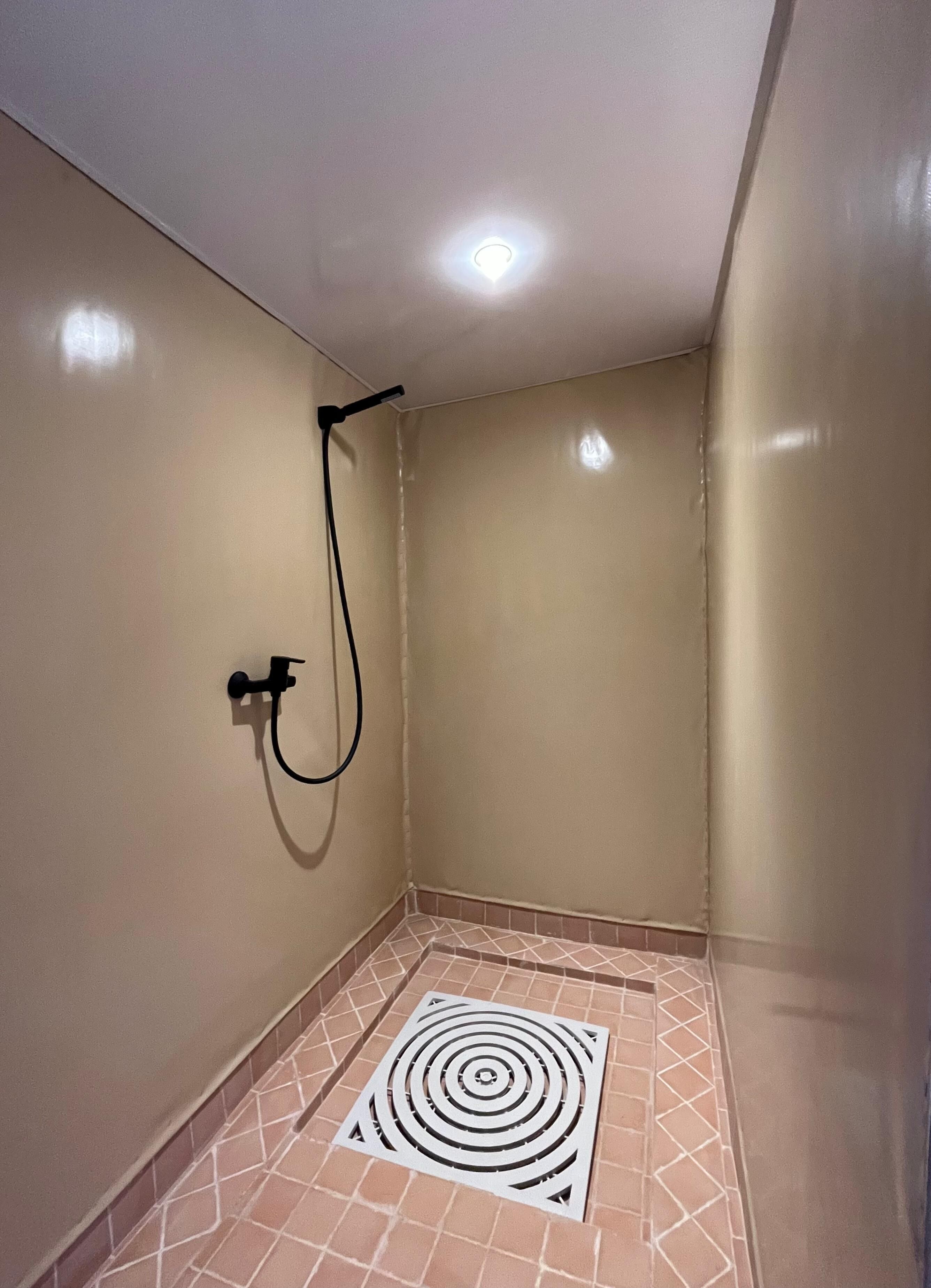 A small, enclosed shower area with a tiled floor and a circular drain.