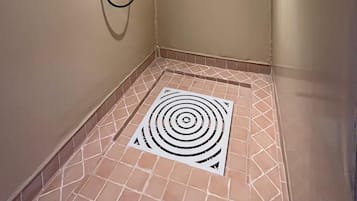 A small, enclosed shower area with a tiled floor and a circular drain.