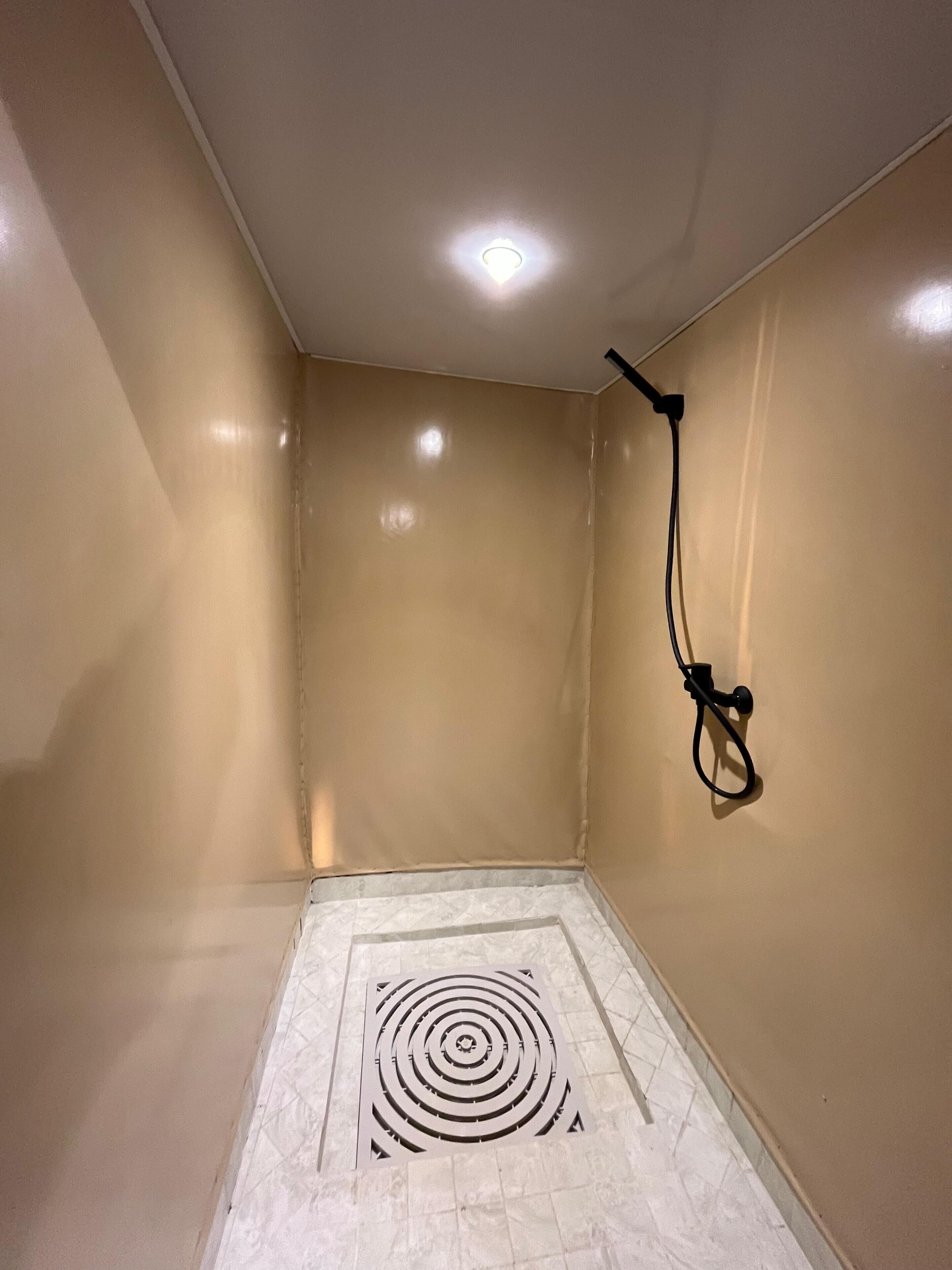 A room with beige walls, a white tiled floor, and a ceiling with recessed lighting.