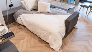 A modern bedroom with a bed, bedside table, and a TV. - 1 Bed Apartment, with a balcony city & canal view in Manchester City Centre! By Kammili Properties (Manchester)