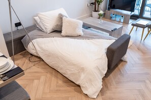 Ein modernes Schlafzimmer mit Bett, Nachttisch und Fernseher.