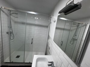 A modern bathroom with a glass-enclosed shower, a white sink, and a mirror.