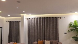 Una sala de estar moderna con dos sofás, una mesa de centro y un ventanal con cortinas.