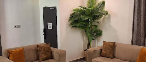 Una sala de estar moderna con dos sofás, una mesa de centro y una planta grande en maceta.