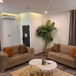 Una sala de estar moderna con dos sofás, una mesa de centro y una planta grande en maceta.
