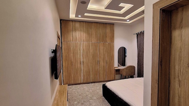Un dormitorio moderno con cama, armario de madera y tocador con espejo.