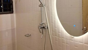 Un baño con ducha, inodoro y espejo.