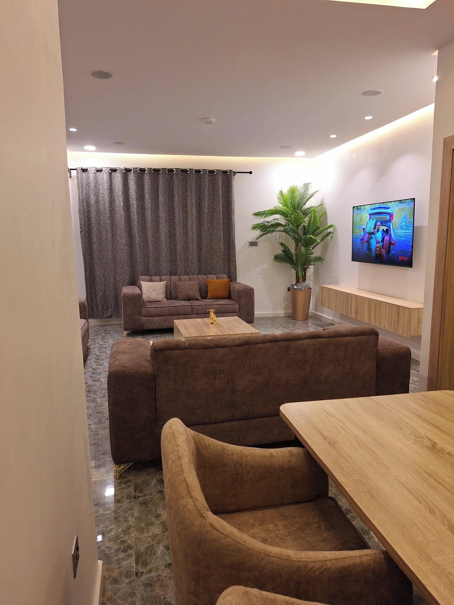 Uma sala de estar moderna com sofá, mesa de centro e TV fixada na parede.