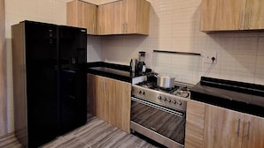 Una cocina moderna con armarios de madera, un refrigerador negro, una estufa y un salpicadero de azulejos.