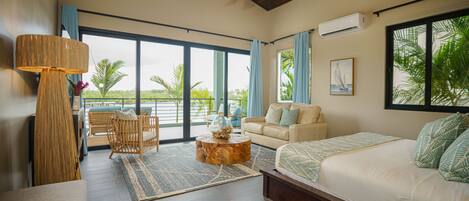 A spacious living room with a large window, a ceiling fan, a sofa, a coffee table, and a view of the outdoors.