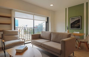 Uma sala de estar moderna com um sofá, poltrona e uma mesa com livros.