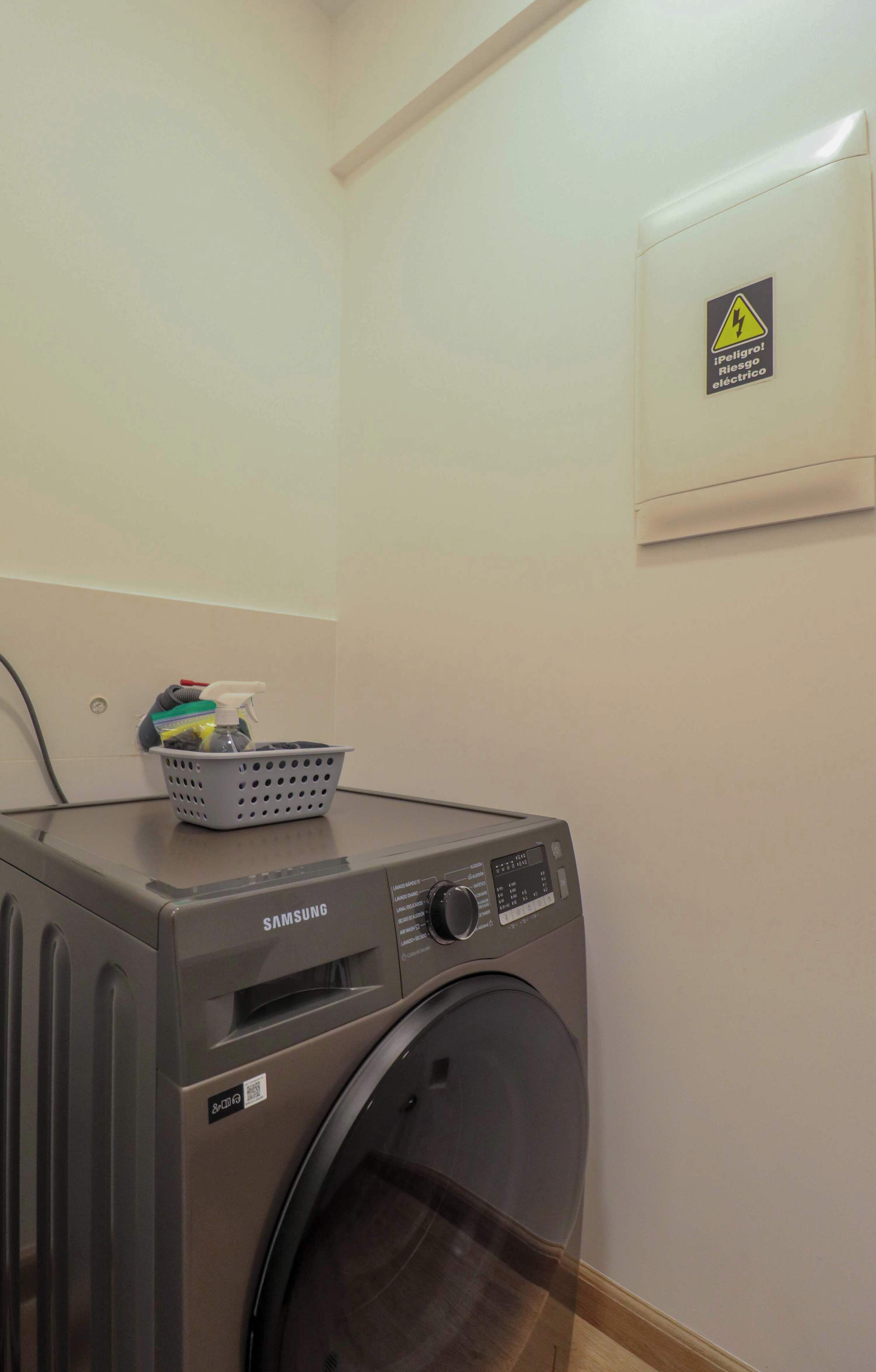Een Samsung wasmachine in een wasserij, met een mand vol wasgoed er bovenop.