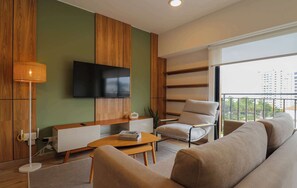 Uma sala de estar moderna com televisão de tela plana na parede, um sofá, uma mesa de centro e uma poltrona.