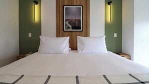 A hotel room with a large bed, two bedside tables, a nightstand, a framed picture on the wall, and two wall-mounted lights. - w* | Welcoming 2BR w/ Balcony in Miraflores (Miraflores)