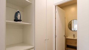 A white closet with shelves and a door leading to a bathroom with a sink and mirror. - w* | Welcoming 2BR w/ Balcony in Miraflores (Miraflores)