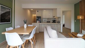 A modern kitchen with white cabinets, a dining area with a wooden table and white chairs, and a living area with a white sofa. - w* | Welcoming 2BR w/ Balcony in Miraflores (Miraflores)