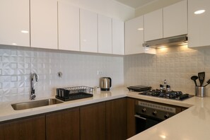 Een moderne keuken met witte kasten, een roestvrijstalen spoelbak, een waterkoker en een gasfornuis.
