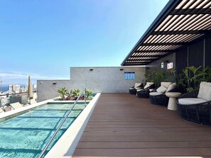 A rooftop pool area with a view of the city skyline, outdoor seating, and a clear sky. - w* | Upscale 3BR w/ Balcony in Upscale Miraflores (Miraflores)