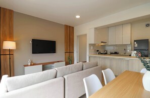 Un salon moderne comprenant un canapé, une table à manger et un coin cuisine avec des placards et des appareils électroménagers.