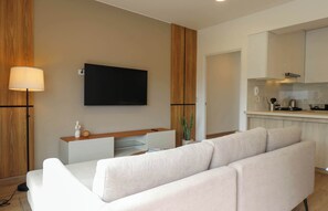 A modern living room with a flat-screen TV, a sofa, a lamp, and a wooden accent wall. - w* |  Airy 2BR w/ Balcony in Prime Miraflores (Miraflores)