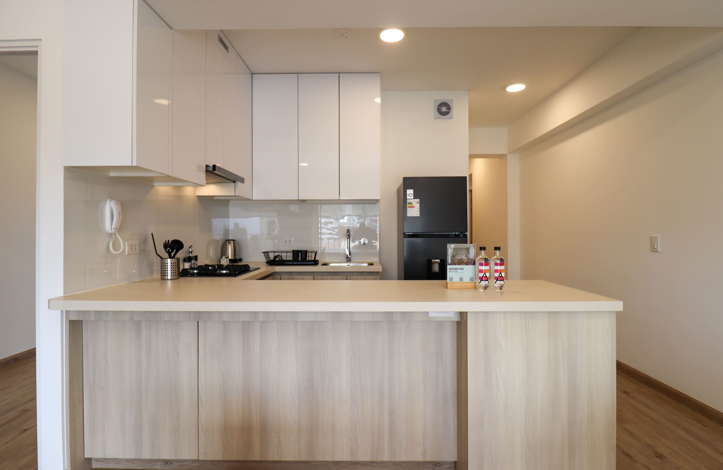 A modern kitchen with a central island, white cabinetry, and a black refrigerator.