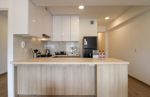 Une cuisine moderne dotée d’un îlot central, de meubles blancs et d’un réfrigérateur noir.