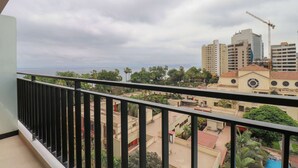 Ein Balkon mit Blick auf eine Stadtlandschaft, darunter Gebäude und ein Baukran.