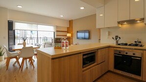 Eine moderne Küche mit Holzausstattung, einem eingebauten Backofen und einem Essbereich mit Tisch und Stühlen.